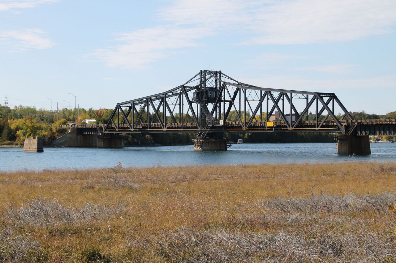 Spanning the North Channel between Goat Island and Manitoulin Island, the former Canadian Pacific Railway Swing Bridge was located at Mile 38.27 Little Current Subdivision. The bridge was opened to rail traffic in October 1913 providing a rail link to Little Current, the western terminus of the Algoma Eastern Railway. In November 1945 modifications to add a vehicular deck for road traffic were completed providing a road link to Manitoulin Island. The bridge was shared by rail and road traffic until the abandonment of the rail line into Little Current. Now known as the Little Current Swing Bridge, it carries a single lane of road traffic and a pedestrian sidewalk. The bridge is a designated Ontario Heritage Property. A new bridge is planned to be built to the west of the existing bridge.
