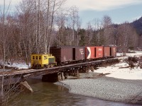 On Vancouver Island, and between the Lake Cowichan interchange with the E&N and their mill at Honeymoon Bay, Western Forest Industries operated a 1929 Plymouth WLG-8 locomotive numbered 40 (previously 7) as required to bring empties to the mill and take resulting outbound loads to the interchange for furtherance to off-Island destinations.  Here, WFI 40 has three empties in tow and is crossing the Robertson River bridge westward on a cool Monday 1974-03 -11, with less than two miles to go to reach the mill.

<p>Number 40 went to Westcan Terminals at Ogden Point in Victoria in 1978, where it regained its number 7, then went to the Ladysmith museum in 1987 and then in 1996 to the Kaatza Museum in Lake Cowichan in 1996, where it is now on display, just 6 km (as the raven flies) east-northeast of this photo location.
