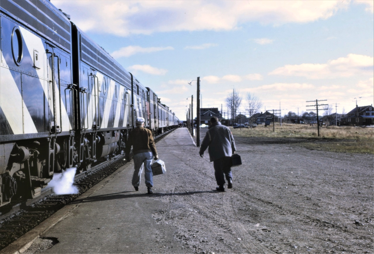 In a scene that is played out hundreds of times every day (even today), but not often recorded, the engine crew has brought CN train 105, the Panorama, into their away from home terminal of Foleyet, Ontario and are headed to the bunkhouse.  My father, on the left, was the engineer.  The train is stopped with the coaches at the station, but with 8 head-end cars this day, the engines are near the west end of the platform.  Three units were the standard power for this train, but on this date, it had 4, three GMs and 1 MLW.