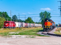 The crew of the BNSF's internal shortline BNML (Burlington Northern Manitoba Ltd) pause outside their HQ at the corner of Taylor Avenue and Lindsay Street waiting for permission to enter the CN Rivers Sub to interchange with CN at Fort Rouge. Meanwhile the (timetable) westbound CP "Altona" creeps up to the crossing awaiting their signal over the CN Rivers Sub at St. James Junction with CP GP20C-ECO's 2217-2325 and a lengthy consist.