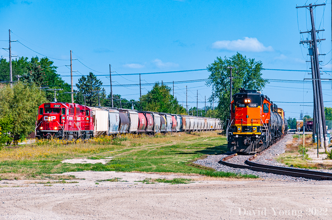 The crew of the BNSF's internal shortline BNML (Burlington Northern Manitoba Ltd) pause outside their HQ at the corner of Taylor Avenue and Lindsay Street waiting for permission to enter the CN Rivers Sub to interchange with CN at Fort Rouge. Meanwhile the (timetable) westbound CP "Altona" creeps up to the crossing awaiting their signal over the CN Rivers Sub at St. James Junction with CP GP20C-ECO's 2217-2325 and a lengthy consist.