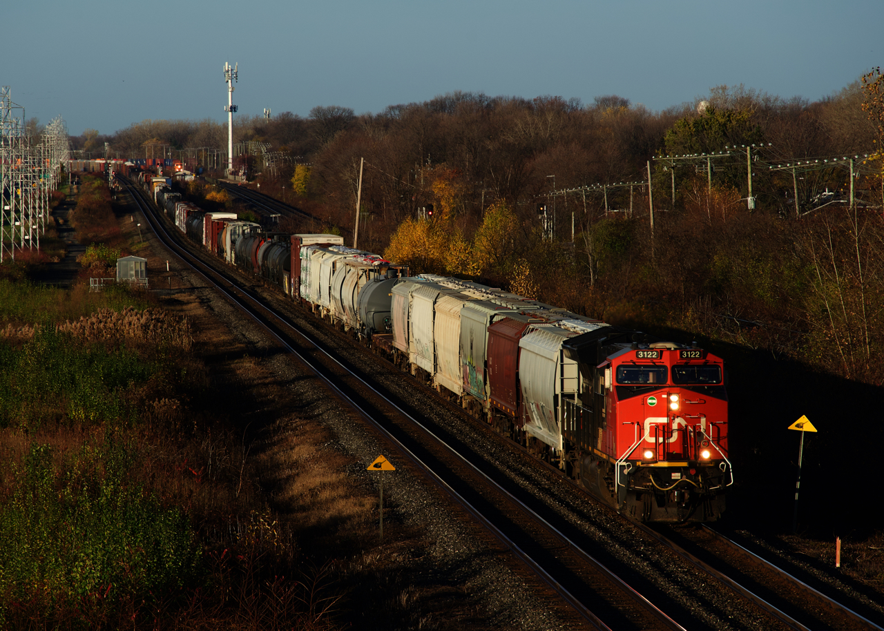 CN 310 heads east through Beaconsfield with ex-GECX unit CN 3122 leading. In the far distance CP 118 is seen, with CP 8757 leading.