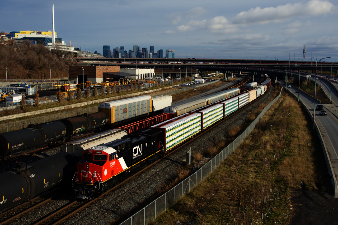CN 3305 (recently rebuilt from Dash9 CN 2563) is leading CN 305 as it passes CN X306, as well as cars parked on the Freight Track and Track 29.