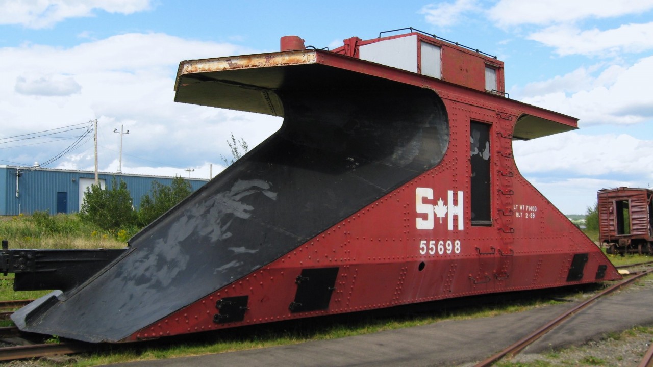 Former CN plow 55698 wears the faded colours of the Salem & Hillsborough Railway shortly after the railway ceased operations. After excursions ended most of the track was removed and the site became the New Brunswick Railway Museum. In recent years most of the equipment that had been painted in SH colours has been repainted into the paint schemes of their original owners. This included 55698 and she now wears brown paint with CN lettering.
