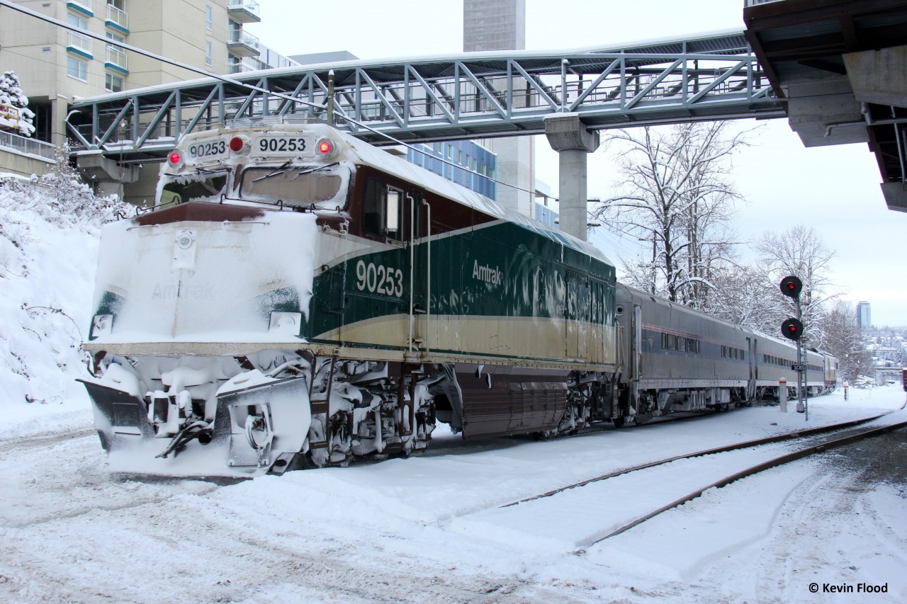 The daily Amtrak Cascades train is pictured passing the Sapperton Skytrain Station in the New Westminster area of Vancouver after an infrequent heavy snowfall. Supposedly, this unit is a baggage car and the lead unit is WSDOT 1404, which appeared to be a Siemans Charger unit. WSDOT stands for Washington State Department of Transportation.