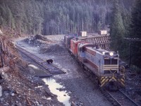 On Vancouver Island, CP’s E&N division operated a branch westward from Parksville to Port Alberni, with numerous wood trestle bridges due to the mountainside terrain.  Two large ones were just east of Stokes, 14 rail miles east of Port Alberni, and maintenance expenses and fire risks prompted bypasses on curved and culverted fills in 1971.  Here at mileage 24.4 immediately east of Stokes siding, Baldwins 8012 and 8001 ease a westward train across the bridge over Four Mile Creek, with the new grade and track approaching readiness for connection and service.

<p>Only a few photos of 8012 are in my collection, as befitting its thirteenth status in the fleet it was the first to expire, due to an electrical fire on 1973-02-19 on the severe upgrade a few miles east and on a similar westward run as in the photo.