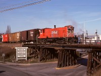 Occasionally, typically to verify some just-completed maintenance such as traction motor changeout was okay, the 0600 yard crew at Victoria was provided a Baldwin roadswitcher instead of the usual MLW S-3, and on Thursday 1975-03-06 that was the assignment for 8003.  Immediately north (by timetable, west by compass) of the Johnson Street bridge over Victoria harbour, a spur connected down a grade to an interchange with CN, and in this shot the yard crew is returning upgrade and crossing over the Harbour Road bridge just before reaching the main track switch.  This photo was taken from an overpass of Esquimalt Road that is today’s end of track at mileage 0.2.

<p>Completely unknown to me at that time, it was only five days before shutdown of all seven remaining Baldwin roadswitcher units was begun, so this was a happy coincidence of sunshine and blind luck timing and my camera if ever there was one.