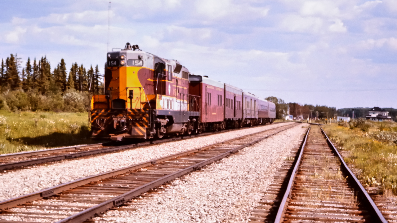 After a brief station stop, AC 154, an EMD GP7 built in March 1951 leads a small passenger train northbound out of Oba, ON in July of 1976. This Algoma Central consist includes AC 154, AC 74 steam generator unit, AC 201 express baggage, AC 209 express baggage, AC 422 coach, and, AC 424 coach. The CN Oba station on CN's Ruel Sub. can be seen at the right of the photo. I was working in Oba at the time on a CN regional tie renewal gang and took the opportunity to walk across CN's yard and onto the ACR yard tracks to capture this movement as it continued its journey to Hearst, ON.