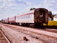 Having seen the head end in a previous post, here is the tail end of an Algoma Central passenger train departing Oba, ON in July of 1976. After a brief station stop, AC 154, an EMD GP7 built in March 1951 is leading this train northbound out of Oba headed for Hearst, ON. The consist from front to rear includes AC 154, AC 74 steam generator unit, AC 201 express baggage, AC 209 express baggage, AC 422 coach, and, AC 424 coach supporting the marker lamps. A string of cars can be seen on the CN/ACR connecting track at the left, and a couple of resident dwellings on the right. Note the nuts on the ACR rail joint bolts all face the field side, unlike the CN next door that staggers the bolts & nuts in each joint. Looks like a few tie plates will be replaced in the not-too-distant future.