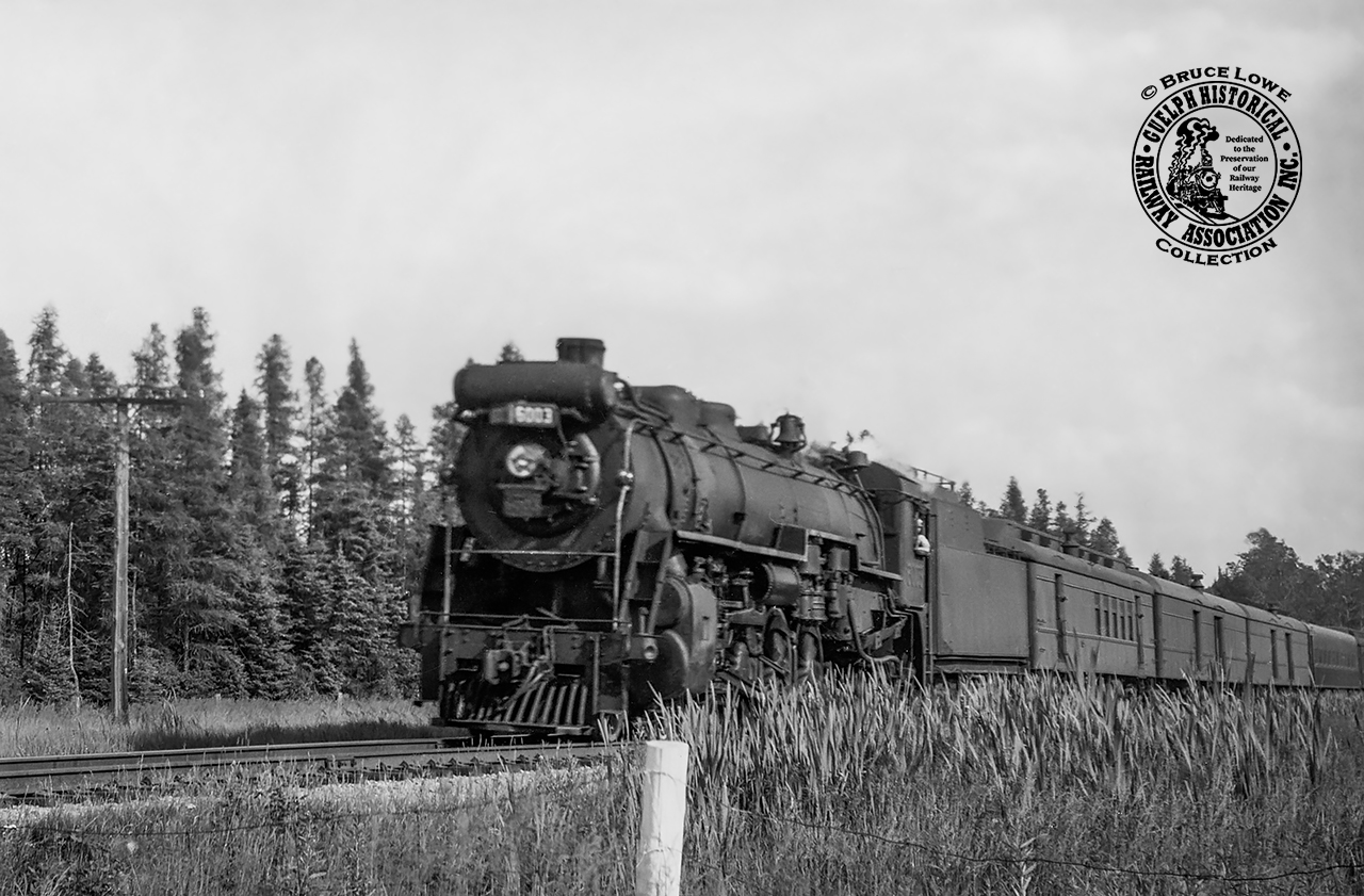 CNR U-1-a Mountain 6003 is southbound along the Huntsville Sub (Gravenhurst - Nipissing Jct./North Bay) near the cottage community of Lake Bernard.  Despite five passenger trains each way almost daily, Lake Bernard would only be served by trains 41 (north/westbound) and 44 (south/eastbound) during the summer months as a flag stop.  The 1956 season saw service from June 9 to September 8.  Based on the sun angle this appears to be Saturday only train 56 which operated during the summer months from June 30 - September 1, 1956, departing the town of Sundridge - six miles north - at 0927h.  Today the Huntsville Sub makes up the northern section of the Newmarket Sub.[Geotagged location may not be exact.]