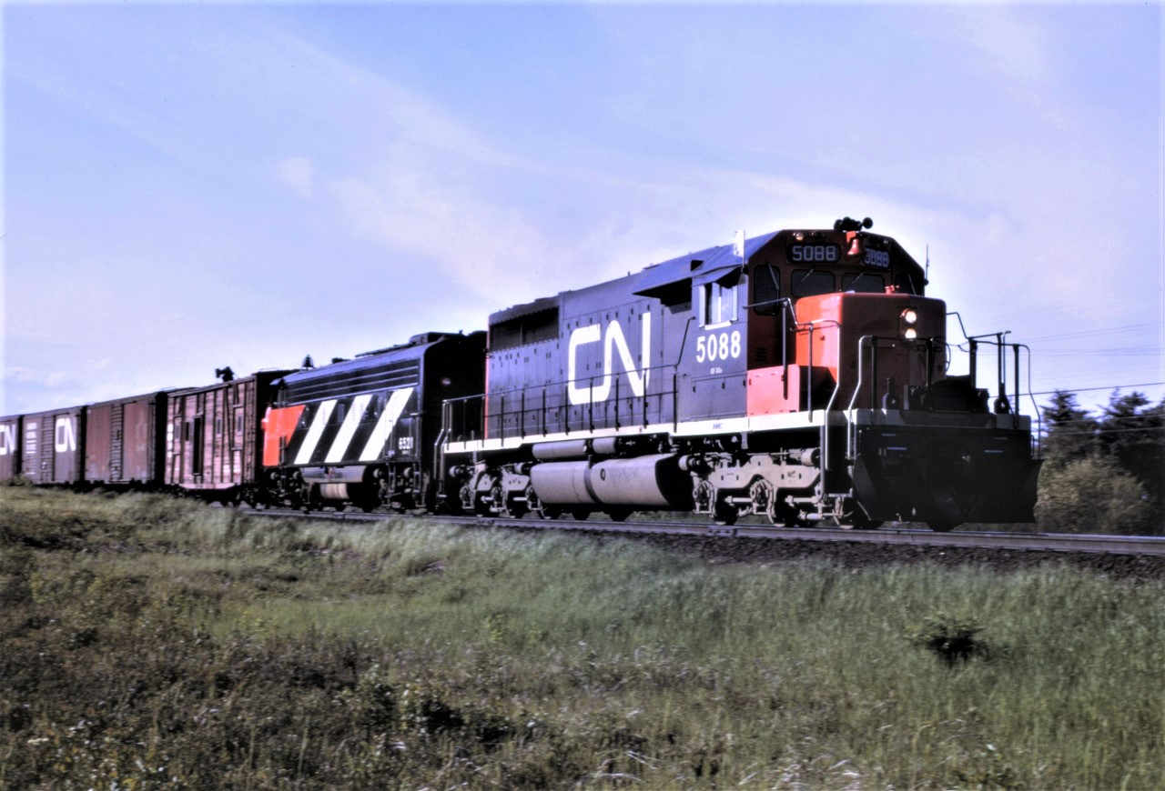 CN train 474 heads south out of Capreol with an unusual consist which includes SD40 5088, FP9A 6521, and a road repair car first up.