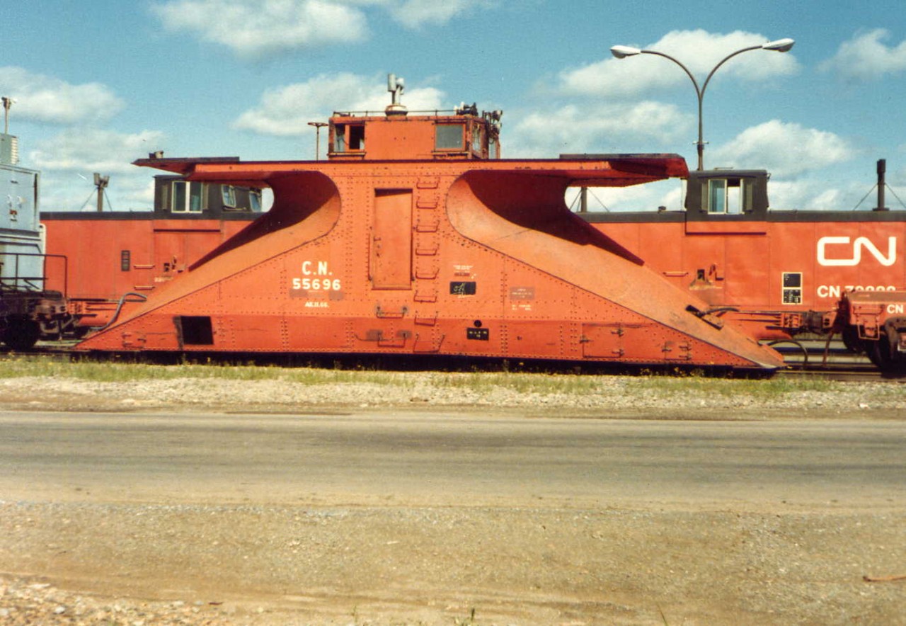 While on an Atlantic Region road trip in August of 1979 to test a new tie inserter for CN in Halifax, NS, I stopped in for a visit at CN Gordon Yard in Moncton, NB and came across several pieces of idle OCS equipment. Double ended snow plow CN 55696 was sitting in a line with other units (CN Blue Fleet Transportation Dept. accommodation unit to the left, and a scale test car to the right). Information in two recently posted photos of these rare bi-directional plows indicates there were only four of the specialty units constructed by CN at Transcona shops in Winnipeg, MB in 1939. When new, this unit, like other snow plows and flangers was painted box car red, but now sits covered in the once very popular for CN Work Equipment, CN No. 12 orange (CN Spec. 470-9N). Over the years, and before CN began accepting new Work Equipment in industry standard MoW yellow paint, a few locomotive cranes received this paint treatment as well. I do not recall any Jordan spreaders being painted No. 12 orange.