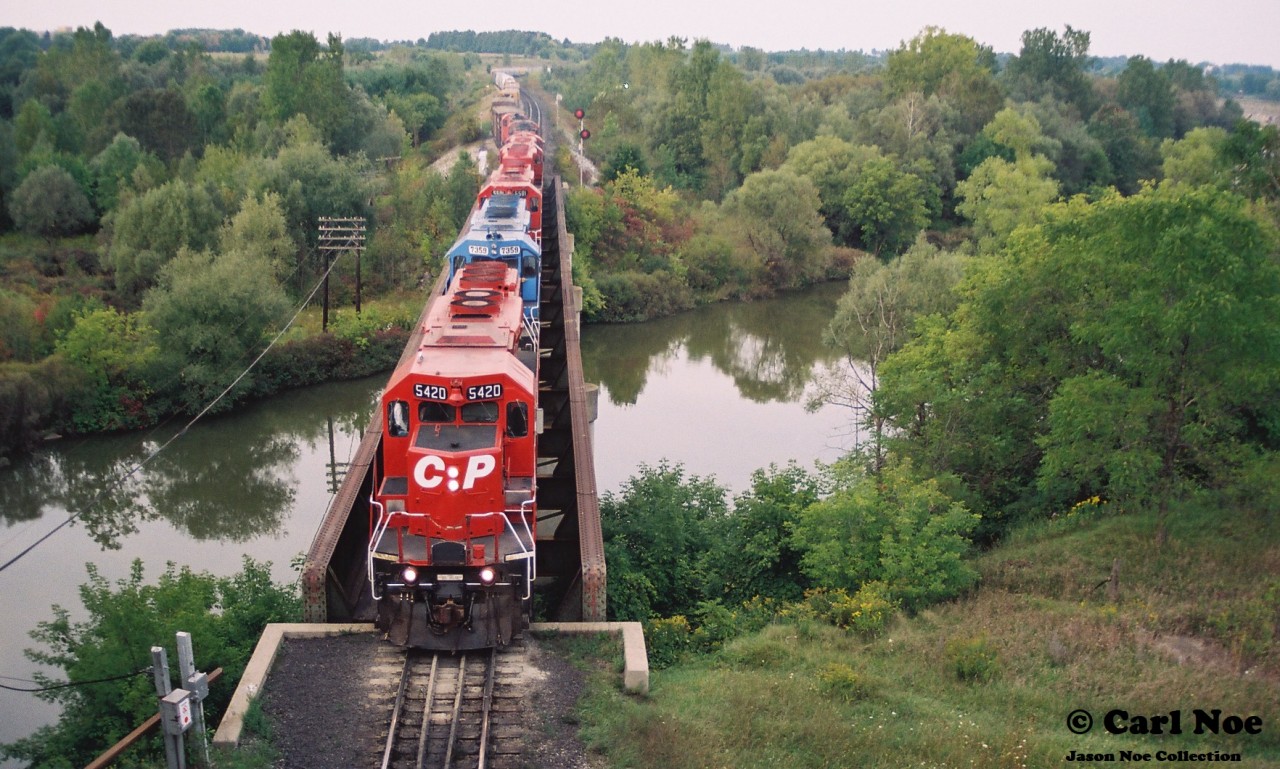 During a late summer evening, CP train 271 slowly departs the west siding switch Coakley in Woodstock on the Galt Subdivision with SD40-2 5420 leading a lengthy consist after meeting an eastbound. 
 
CP 5420 is former Kansas City Southern Railroad 675 and it would go on to enjoy a long second life on CP.