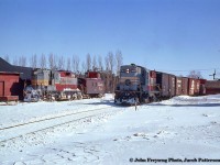 Canadian Pacific train 91, the Teeswater Sub wayfreight out of Orangeville, passes through Grand Valley with three boxcars and one of CP's early steel, end cupola vans (437268 - 437404 series) bringing up the rear. On the siding at left, plow extra 8424 sits uncoupled from its plow alongside Tindall Feeds.<br><br>CP 8742, rebuilt to CP 1815, would survive <a href=http://www.railpictures.ca/?attachment_id=13138>into Ottawa Central days</a> until the OC was purchased by the CN. 8242, rebuilt to 1505, would be scrapped in 2011.<br><br><i>John Freyseng Photo, Jacob Patterson Collection Slide.</i>