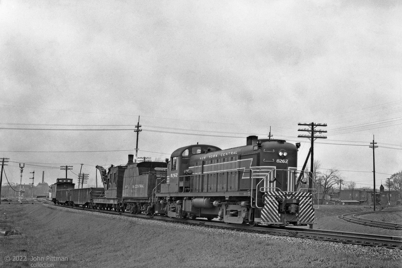 The Ottawa and New York Railway ran from Ottawa to Cornwall, where a set of railway bridges across the St Lawrence River connected it to the New York Central System.
O & NY was majority-owned and operated by the New York Central Railroad from 1905 through 1957. Construction of the St. Lawrence Seaway in 1957 required the removal of the Cornwall railway bridges, severing the connection with New York state.  
The line was not viable after that.
The data for my negative/positive places this scene of ALCo RS-3 NYC 8262 in Ottawa on 23 September 1952.
Its train consists of a 1912 Russell steam crane with tender, 2 gondolas and caboose.
Crane NYC X126 was 40 years old at the time. Its 10 ton capacity was not for heavy lifting.
Perhaps the location can be identified more precisely; the configuration and quantity of signals suggests a diamond crossing or significant junction.
Information Sources:
Wikipedia article "New York and Ottawa Railway"
https://www.nyc-ottawadivision.com/   
https://www.canadasouthern.com/caso/NYC-MODELS-MOFW.htm    (NYC crane roster)