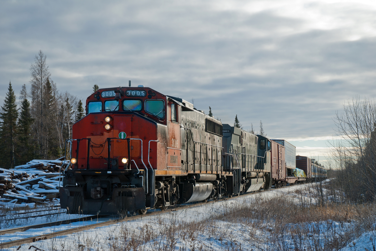 Keewatin Railway's signature mixed train is seen northbound at Root Lake Manitoba with GP40-2W HBRY 3005 and M-420W KRC 2401 up front.  Behind the power are a pair of flat cars bracketed by a set of HBRY 40 foot box cars followed by the passenger portion of the train.  I can't remember what led me up to this portion of the country in late November but I would certainly like to do it again in the summer.