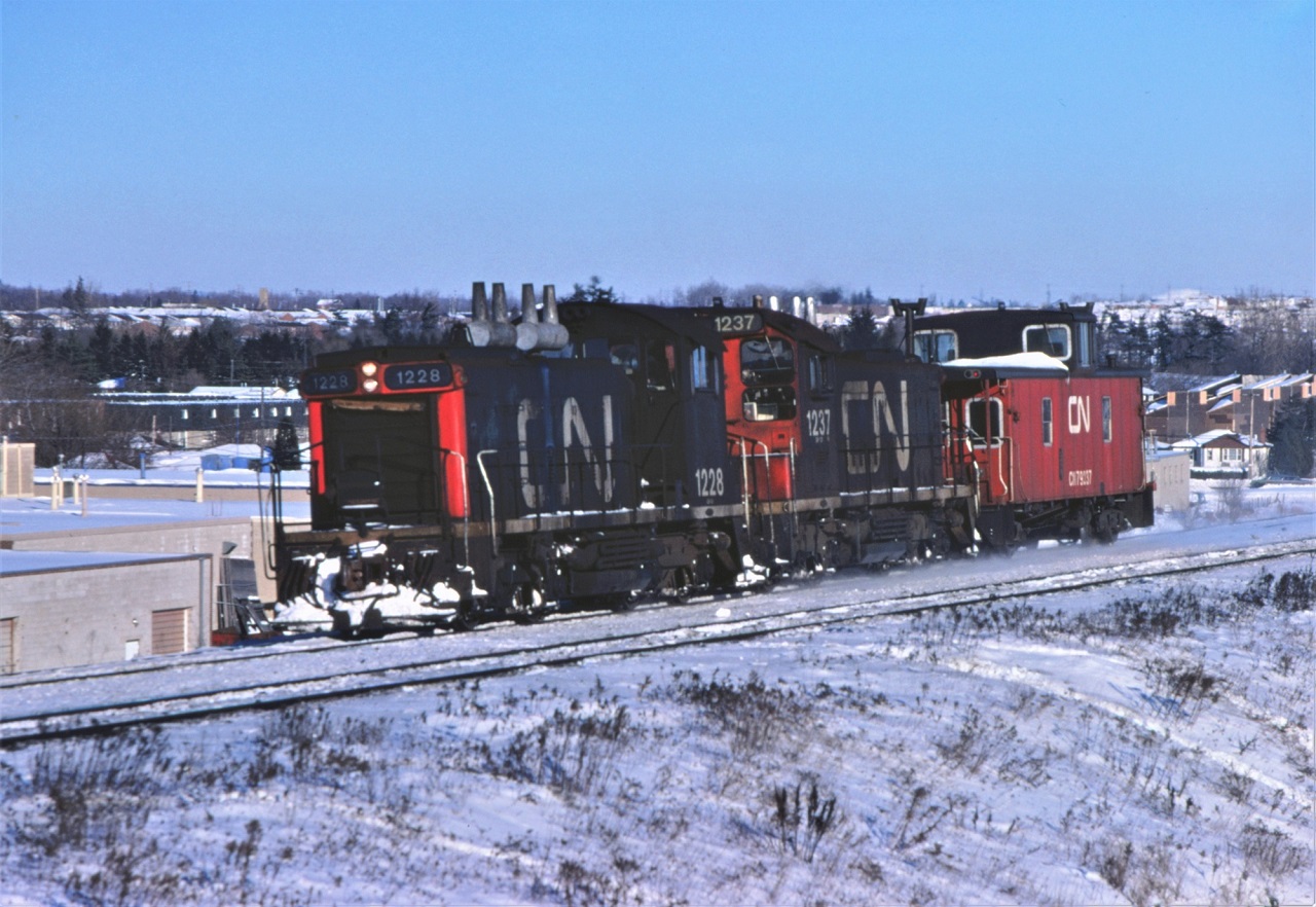 A pair of CN SW1200RS units from class GR-12f built in 1956 rush back to Toronto Yard with a van hop movement.  The units are 1228 and 1237.  The units may be from the same order, but there are many differences.
1228: small number board numbers; grey spark arresters; low CN symbol; low cab number.
1237: large number board numbers; silver spark arresters; high CN symbol; high cab number.

Hard to believe this photo was taken 45 years ago.