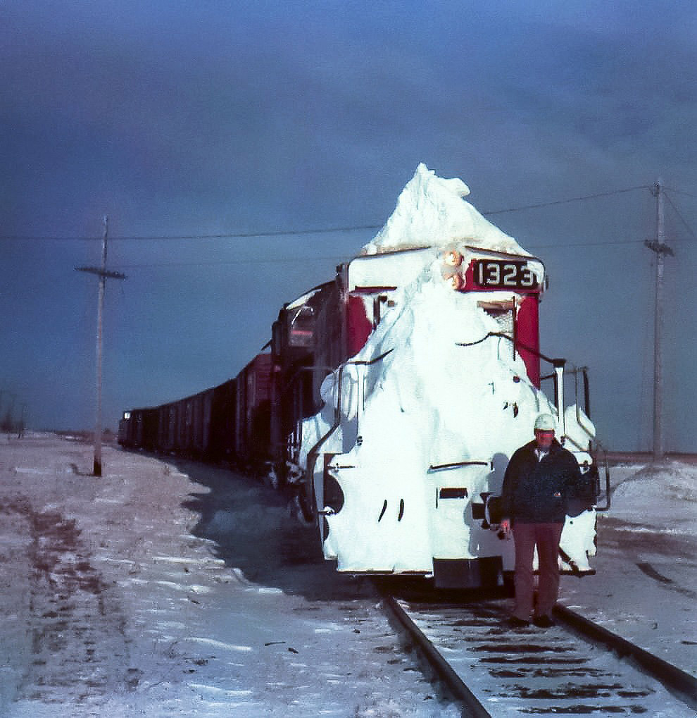 No plow? No problem! Coming up on 45 years ago this month, CN 1323 leads the way freight into Jarvis from Hagersville on the west leg of the wye which is the Hagersville Sub. The Roadmaster (my Dad) has inspected the front of the unit and is satisfied that the cuts between Hagersville & Jarvis have been cleared. :-) The Pyle National dual sealed beam headlight with incandescent bulbs produces enough heat to keep the snow melted from the lenses. That won't happen with todays LED lights. The radiator is completely covered so the cab should be nice and warm. While there is not much snow on the ground, the numerous cuts along the route from Rymal in Hamilton to Jarvis can fill in quickly and become major problems if not attended to.  CN 1323 taken care of that on this cold January 25, 1978 day.
