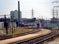 An A-B-B set of GMD F-units (lead by possibly CN 6526) heads northbound through mid-town Toronto with CN's Super Continental, snaking around the curves of the Newmarket Sub north of Davenport diamond on the approach to <a href=http://www.railpictures.ca/?attachment_id=27159><b>St. Clair Avenue station</b></a>. Timetables suggest this is train #103 (formerly #3), that had departed Union Station downtown just after 3pm.<br><br>The section of track here in the St. Clair/Davenport/Caledonia area had been grade separated in the late 1920's/early 30's, that coincided with demolition of the old GTR Davenport Station and construction of a new brick St. Clair Avenue Station. Visible in the background are the large headhouses of the Canadian Generel Electric (ex-Canada Foundry) Davenport Works plant, served by both CN & CP. Power lines are from Toronto Hydro's nearby Witshire transformer station, that also had a siding.<br><br>Due to its proximity to Little Italy, various food and produce distributors established buildings here to receive boxcars and reefers of fresh produce, grapes, etc, sometimes from as far away as California. On the right (west side of the tracks) is Pietro Culotta Grapes, which had two buildings with multiple sidings and loading platforms. Out of frame, A&P had a distribution warehouse nearby and sidings coming off the same spur. On the left (east side) of the corridor are Caledonia Food Distributors (pictured, note loading doors along siding), Darrigo Brothers, and the Meschino Banana Company. CN also had team tracks and a ramp track this area.<br><br>Remnants of sidings and much of the old buildings here did survive into the late 2000's before progress and redevelopment took hold. The Newmarket Sub, single tracked at one point, will probably get double-tracked again once Metrolinx finishes its Davenport diamond grade separation project.<br><br><i>Tom Gascoigne photo, Dan Dell'Unto collection slide.</i>