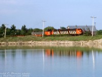 During the brief period in time when solid A-B-A sets of zebra-striped F-units were the order of the day on the Steel Train, CN 9173, 9195 and 9166 handle today's train #725, reflecting their stripes in the pond just south of Hagersville as they roll past on the Hagersville Sub.<br><br><i>Harold E. Brouse photo, Dan Dell'Unto collection slide.</i>