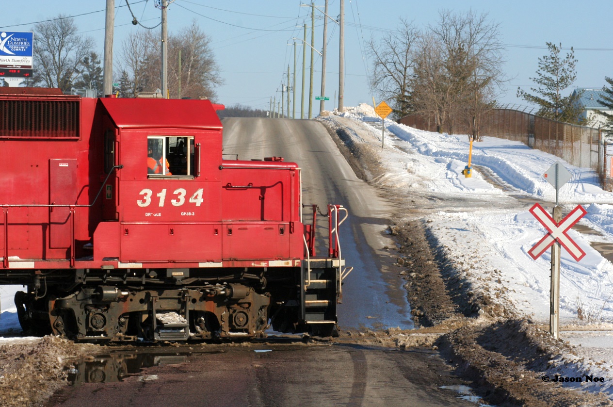 An Extra CP Wolverton Job with 3134, 3117 and 3045 is switching over Greenfield Road in Ayr, Ontario on the Ayr Pit Spur during a winter afternoon.