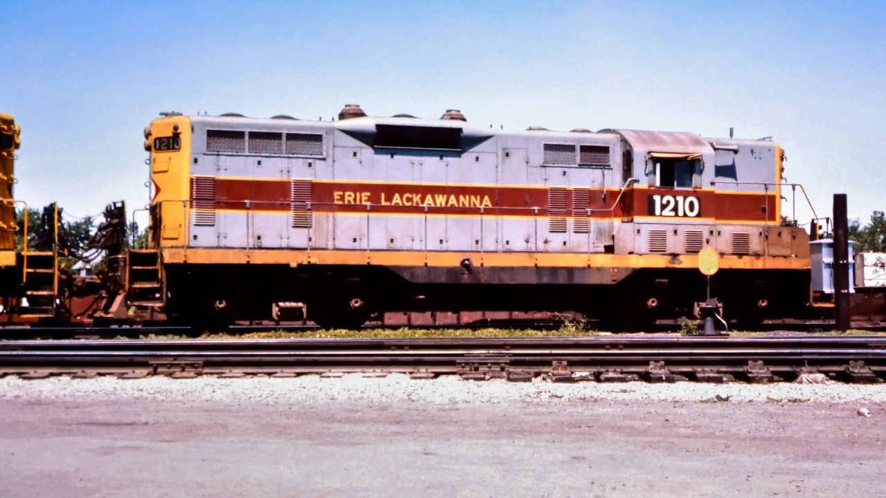 While working on a CN tie renewal gang stationed in Fort Erie, ON in the summer of 1976, I came across a couple of Erie Lackawanna units idling away in the yard.  Here, EL 1210 with its patched road number sits coupled to sister unit EL 1405 on this beautiful mid-summer afternoon. The exaggerated shadow of the single trumpet horn almost looks like it was painted on the short hood.