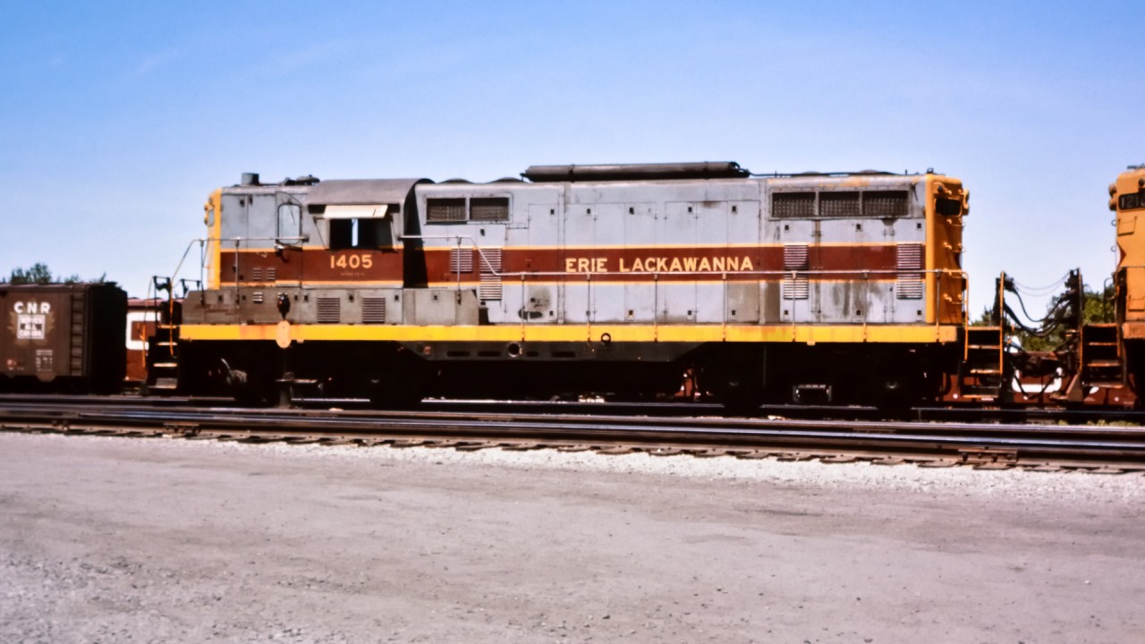 While working on a CN tie renewal gang stationed in Fort Erie, ON in the summer of 1976, I came across a couple of Erie Lackawanna units idling away in the yard. EL 1405 with roof mounted torpedoes sits coupled to sister unit EL 1210 on this beautiful mid-summer afternoon. A freshly painted CN gondola and 40' boxcar can be seen in the background behind the locomotive, while a 40' boxcar with the CNR 'Serves All Canada' maple leaf logo sits at the left.