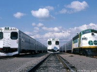 An almost picture perfect lineup: three GO Transit trains sit in Willowbrook Yard awaiting their next call to duty. Cab cars 9852 and 9853 mingle with APCU 9861 (still looking fresh a few months after entering service), all heading up consists of single-level Hawker Siddeley commuter cars. The flag clipped to the rail is "blue flag protection", noting to anyone around that crews are working on that consist in the yard.
<br><br>
<i>Original photographer unknown, Dan Dell'Unto collection slide.</i>