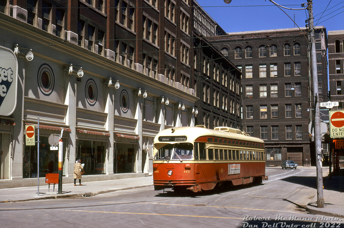 TTC PCC 4451 (A7-class, blt CC&F 1949) gets ready to pull away from the streetcar stop and turn onto Albert Street off James to begin its next trip westbound to Dundas West Station on the Dundas route. It's surrounded by various buildings of the T. Eaton Company (Eaton's): their Budget Store (left), Annex Store (behind), and various factories that made up a large parcel of land Eaton's owned downtown. At the time, Eaton's entire downtown holdings were slated for redevelopment for their new Eaton Centre shopping mall development. Teperman & Sons was already demolishing the old Salvation Army building on the right (out of frame, note the edge of their sign). The rest here would soon follow, including the old Eaton's Queen Street Store.At the time, Dundas streetcars looped here using "City Hall Loop" (the on-street track around Louisa/James/Albert/Bay that was used as the end terminus of Dundas cars at the time, so-named due to proximity to Toronto's Old City Hall), but this track would be removed around early 1975 and the Dundas car extended further east.Robert D. McMann photo, Dan Dell'Unto collection slide.