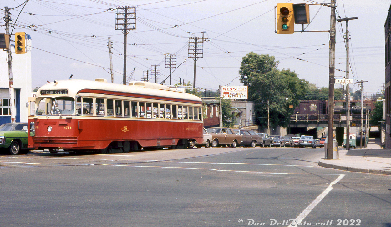 TTC PCC 4756 (A14-class, secondhand from Kansas City MO) is paused at the light before making the right turn onto Weston Road for the short jaunt up to Keele Loop. Either the streetcar is broken down or the operator has hopped off to attend to something, but it has caused traffic to back up coming out of the railway underpass (CN Weston Sub & CP MacTier Sub) and motorists are diverting into the right lane to get by.

On top of the underpass are a few freight cars (including a green-door double-door CN or DW&P lumber service boxcar), probably overflow from the nearby CN West Toronto yards. Webster & Sons Ltd Building Materials had a siding just to the north, one of many small industries in The Junction area to receive rail service.

TTC 4756, originally built as Kansas City 749 by St. Louis Car Co. in 1946 and acquired secondhand by Toronto in late 1957, was retired by the TTC in 1976 and was part of a group of PCC's sold to SEPTA in Philadelphia as their 2242. They were purchased to replace some of the cars SEPTA had recently lost in a carhouse fire, but were in poor shape and only lasted a few years in service for their third owner.

Original photographer unknown (possibly a C.G. Parsons original), Dan Dell'Unto collection slide.