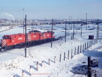  Taken from the third floor GYO washroom window, a set of hump power 1502-1537-1519 passes over the main retarders heading down into 'C Yard' after humping a cut at Toronto Yard (Agincourt) on a chilly Feb 18th 1990. 
1502 is adorned with the Toronto Yard 25th Anniversary stencil. The hump and associated 72 yard tracks is all gone now.  