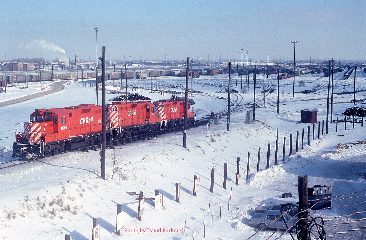 Taken from the third floor GYO washroom window, a set of hump power 1502-1537-1519 passes over the main retarders heading down into 'C Yard' after humping a cut at Toronto Yard (Agincourt) on a chilly Feb 18th 1990. 
1502 is adorned with the Toronto Yard 25th Anniversary stencil. The hump and associated 72 yard tracks is all gone now.