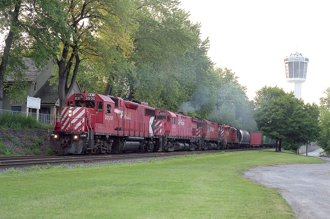For a long time this was a favourite place to wait for CP heading toward Hamilton.  The South Siding Switch Montrose. Unfortunately the track is gone save for a switchback to industries for the Welland local. Adding to the situation is Niagara's endless determination to obliterate on street parking (how dare anyone park for free!) with No Parking signs, fences and what-have-you to discourage motorists stopping here. Not that it matters here any more. The tower in the background has been so ambushed by new highrise hotels I am not sure if it is even visible from this angle any more.
More good old days gone by.  Power on this train is CP 3030, 4233, 4218 and 8235; accelerating now that it has escaped the slow order confines of the Clifton Hill tourist area a mile or so back.