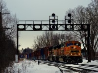 A pair of ex-BNSF SD70MACs with consecutive numbers (QGRY 4016 & QGRY 4015) is leading their train under a vintage signal bridge as they leave CP's St-Luc Yard.
