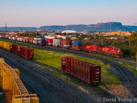 Sunrise in the Intercity. Stored centrebeams in CN's side of "D Yard", while a string of grain loads are observed in CP's portion of "D Yard", blocking the view of Vancouver to Toronto train 110-17, who is moments away from pounding the diamond with CN's Kashabowie Sub in Thunder Bay's Intercity with CP 9771-9564 leading.  