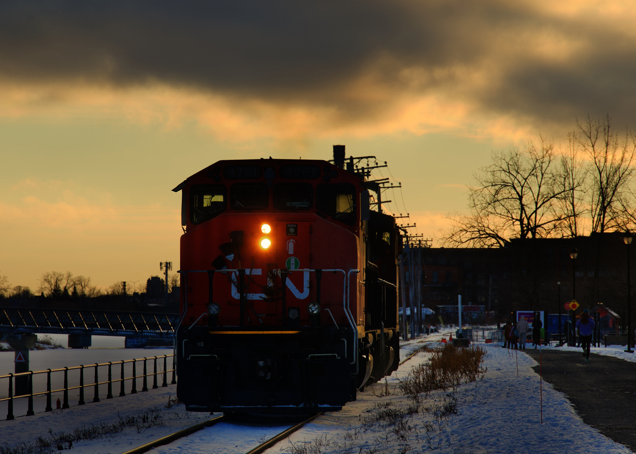 After bringing grain cars to Ardent Mills, CN 500's power is heading back to the main line close to sunset. It is on the East Side Canal Bank Spur, with the snow-covered Lachine Canal at left and a path at right.