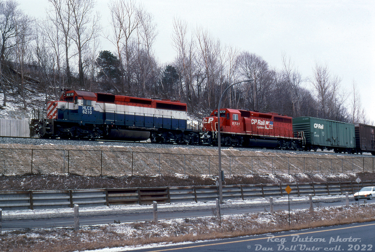 HLCX SD40-2 6210 and CP SD40-2 5731 lead a eastbound/northbound freight alongside Highway 403 at Desjardins near Hamilton Junction. Lease unit HLCX 6210 was formerly BC Rail 742 (pictured still in its old paint), and originally built for the Kennecott Copper Company as KCC 107. Trailing unit CP 5731 sports the new "System" or "Dual Flags" livery that CP introduced in 1993, in part to put greater emphasis on its Canadian and American rail network (now owning the SOO Line, MILW and D&H operations in the US. The shade of red used was SOO's Candy Apple Red). 

The first car following the power is CP 84999, part of a group of 50' newsprint cars that CP added extra height to to accommodate double-stacking newsprint rolls inside.

Reg Button photo, Dan Dell'Unto collection slide.