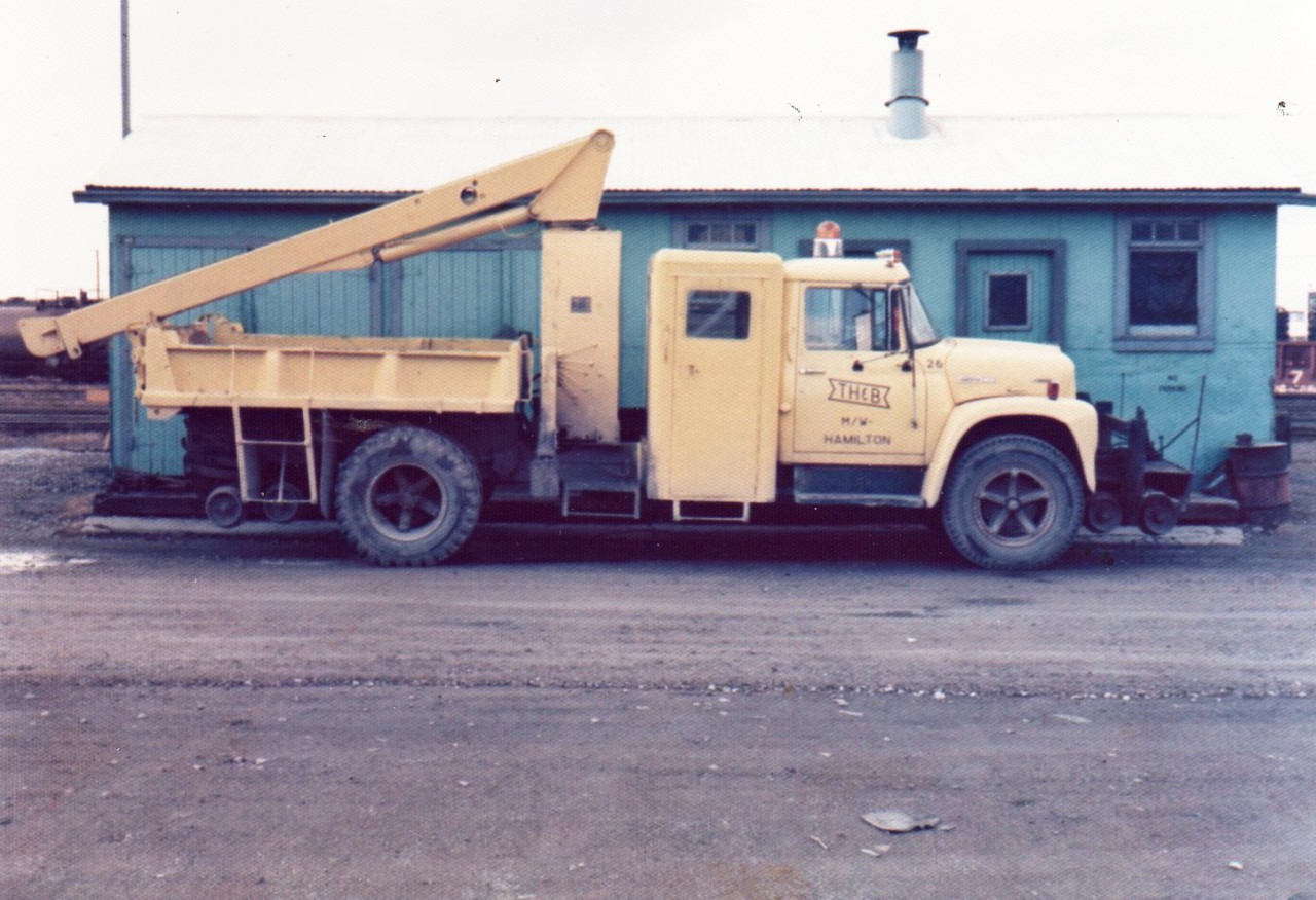 TH&B 26, an International hi-rail boom truck sits next to the Aberdeen yard tool house inside the gate just off Studholme Rd. A nice versatile maintenance vehicle with hi-rail gear, extra crew compartment, squirt-stick hydraulic boom & outriggers, and dump box.