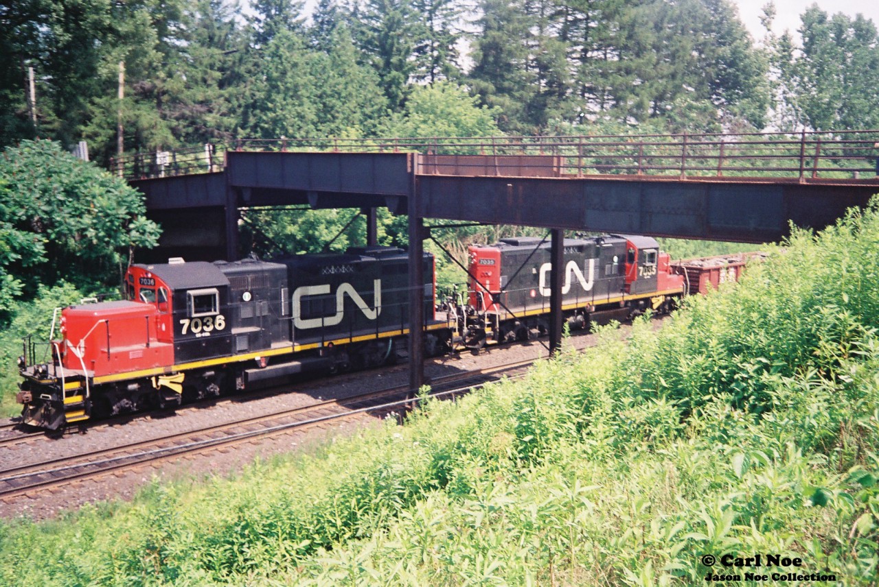 CN 562 with GP9RM’s 7036 and 7035 head west under the original Inksetter Road bridge at Copetown, Ontario on the Dundas Subdivision. At the time, this local originated at Hamilton’s Stuart Street Yard and would often head west to the Paris pit during Sunday’s. Caboose 79707 was on the tail-end on this day.