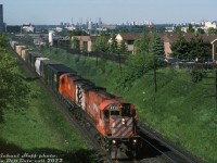 A pair of well-worn 6-axle "Big M's", lead by ratty looking CP M636 4713, head eastbound across CP's Belleville Sub approaching the Victoria Park Avenue overpass on their way to Agincourt Yard. The midtown Toronto skyline is visible in the background, with numerous hi-rise apartment buildings and office towers including the Inn on the Park hotel tower near <a href=http://www.railpictures.ca/?attachment_id=33335
><b>Don Mills</b></a>.
<br><br>
By this time CP's "Big M's" were on their last legs, and retirement for the last ones wasn't far off (the official Big M retirement would be held at St. Luc later that year in December). A handful had one last hurrah when they were pulled for the deadlines and reactivated for a year or two due to CP's chronic power shortage issues. CP 4713 would be retired in December 1993, reactivated in April 1994 but only run for just two months before being sidelined for good.
<br><br>
<i>Michael Hoff photo, Dan Dell'Unto collection slide.</i>