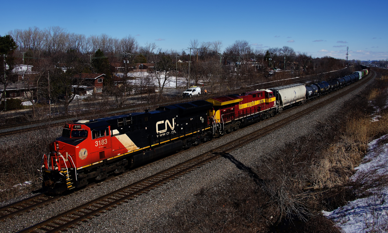 The Wisconsin Central heritage unit is trailing as CN X321 heads west with 138 cars. In the background is a foreman on the CP Vaudreuil Sub.