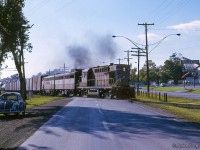 Shortly after an eastbound <a href=http://www.railpictures.ca/?attachment_id=51114>led by a pair of RS10s</a> departed Belleville, another eastbound behind RS10 8469, FB-1 4409, and leased Bessemer & Lake Erie F7A 718 throttles up crossing Highway 2.  My 1958 VW Beetle off to the left.<br><br><i>Scan and editing by Jacob Patterson.</i>
