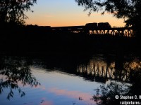 The unmistakable silhouette of a GP9 rolls east over the Grand River in Galt Ontario nearly 10 years ago. The divide between day and night is a losing game for the golden hues of a setting sun, fire reds of a sailors delight contrast with the blues of darkening sky for a few brief moments. T69 crosses the scene, rushing to Guelph Junction with hot cars for the Ontario Southland before racing back home to London in complete darkness.