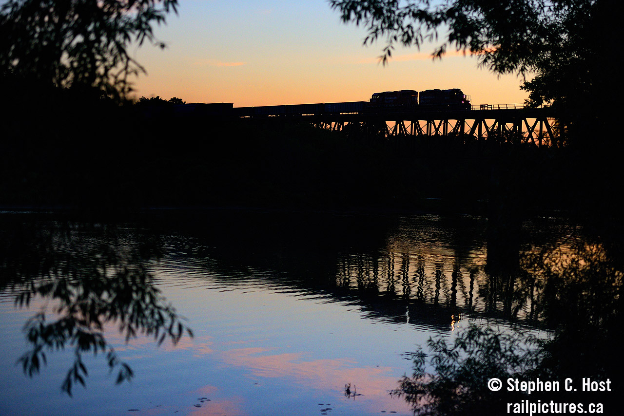 The unmistakable silhouette of a GP9 rolls east over the Grand River in Galt Ontario nearly 10 years ago. The divide between day and night is a losing game for the golden hues of a setting sun, fire reds of a sailors delight contrast with the blues of darkening sky for a few brief moments. T69 crosses the scene rushing to Guelph Junction to drop off cars for the Ontario Southland before racing back home to London in complete darkness.