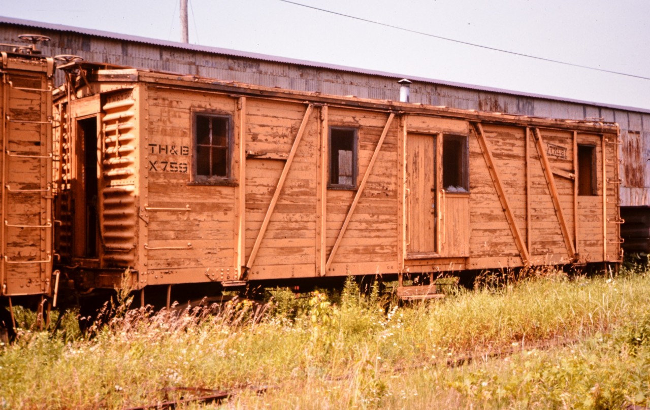 Home away from home. There's no one sleeping in this windowless boarding car tucked away in TH&B's Aberdeen Avenue Yard. At least not any railway employees! Box cars and old passenger equipment converted into MoW service were a mainstay of most railroads prior to the introduction of modular housing units mounted on flat cars in the early 1970's. Lots of neat little features on this old car. Outside braced wood construction, roof level hand brake wheel, roof walk, full length car end ladders, single side coupler cut levers, end doors for between car access, and, the smoke stack for the coal or oil stove is still standing. I spent many a night in old cars like this beginning in 1969 and into the 1970's during my early CN days.