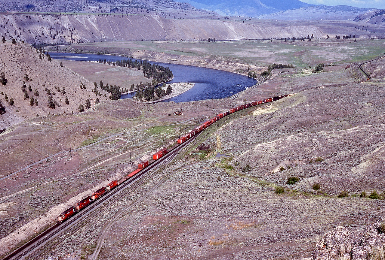 Alongside the Thompson River west from Savona, CP’s mainline climbs to Walhachin, and at the summit on the compass-south side is an outcrop of rock ideal for crushing into ballast, hence the two extra tracks beside the siding.  From the top of that rock, the view eastward on Sunday 1980-06-08 at 1635 PDT included a CP westbound, symbol train 67, with 5664 + 5785 + 57xx + 8501 for power, and in the distance down close to the river, CN’s Ashcroft sub. mainline.

The area from Savona to Walhachin and Semlin to near Ashcroft is not blessed with many easy access points, but is well worth long walks, one of my “happy” places on this planet.