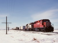 During the bitterly cold winter of 1993-1994, mechanical personnel were deployed to known difficult areas to improve the chances of trains getting over the road without delay, with particular emphasis on “hot” intermodal traffic.  Thus, I was on eastward symbol train 482/03 with SD40-2s CP 5943 and SOO 6622 on Friday 1994-03-04 when we had a meet at Falcon, SK, 108 miles east from Moose Jaw, which presented an opportunity to railfan on pay.  At just under a mile north of the TransCanada Highway, the sound of the idling units competed with the wind singing in the low pole-line wires.