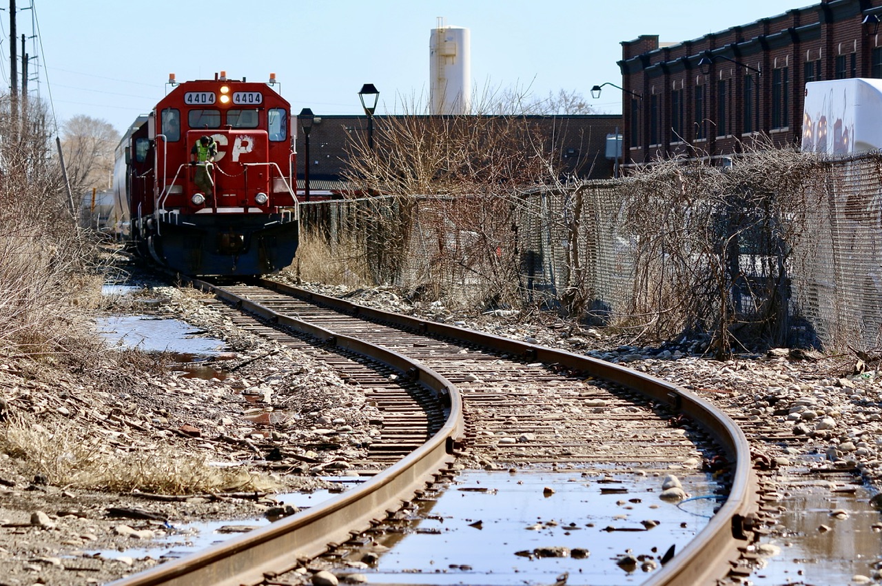 One of those interesting little pieces of industrial railroading left in Toronto. It is unfortunate that lighting doesn’t usually work in the photographer’s favour with the power typicality on the north end of the train and sun over your shoulder. There has been a lot of urban renewal in the area and many rail served customers here have vanished. Thankfully for now a few remain and keep things a bit interesting here. Here 4404 has just finished working the last customer on the Kotex lead and are slowly heading north back to the main with a few cars in tow. An overnight rain storm has covered a lot of the roadbed in places.