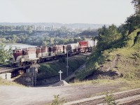 Date not marked, but I know this was mid-June, and the strong sun and late shadow makes this look like it was taken on the longest day, or close.
The shadows play havoc with this one, but still; not a bad shot considering how late the train was coming out of Hamilton.  Appears to be 72, 402 and 75. Not sure of the middle unit.
The cross and the mound in the pic is a 'Do Not Trespass' sign.  No, the gravel was dumped there by the MoW guys. It is not the final resting place of the last trespasser. :o)