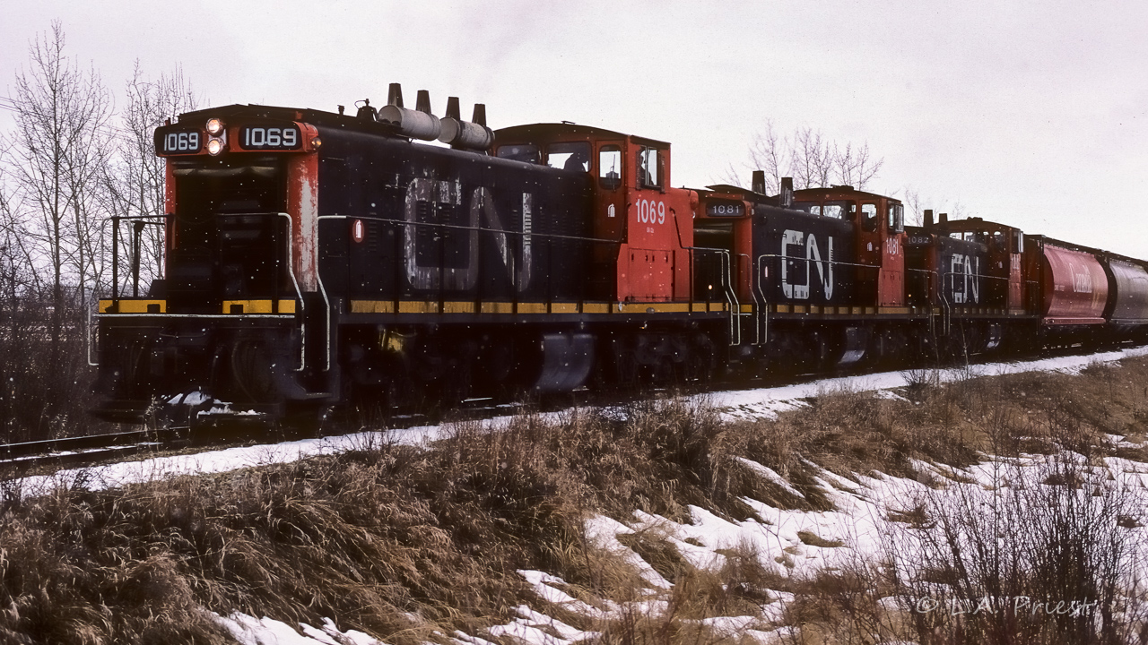 GMD-1's with dandruff :^). The grain extra has just finished picking up 4 hoppers from the elevators in Redwater and now has all 35 loads rolling for Gibbons. Looking at my notes, I shot this at f8 and 1/125, surprised there is no blur in the picture. This photo taken at the Burger Baron crossing (main street) in Redwater at 10:55.